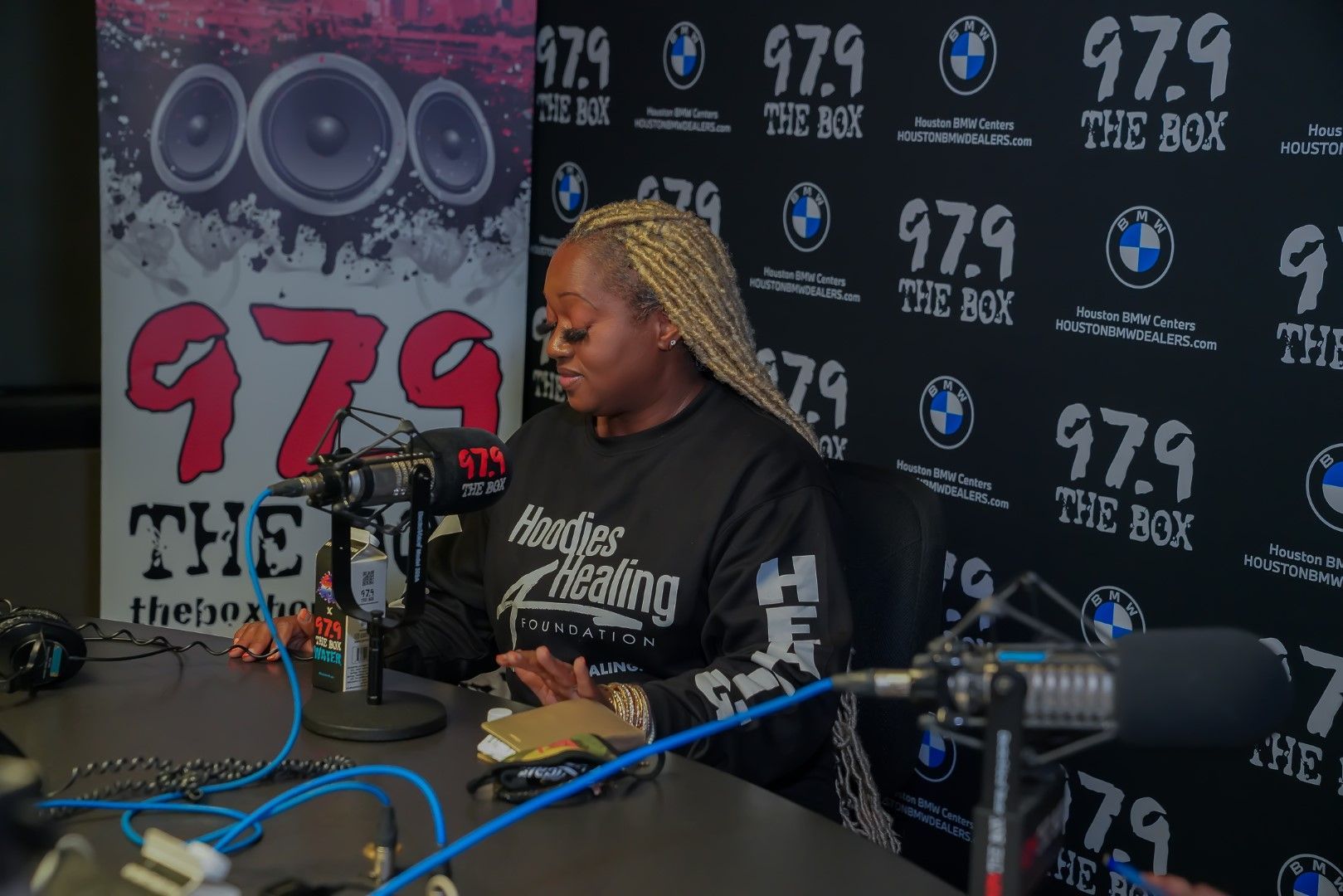 A woman is sitting at a table in front of a microphone.