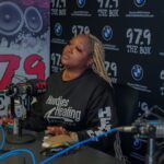 A woman is sitting at a desk in front of a microphone.