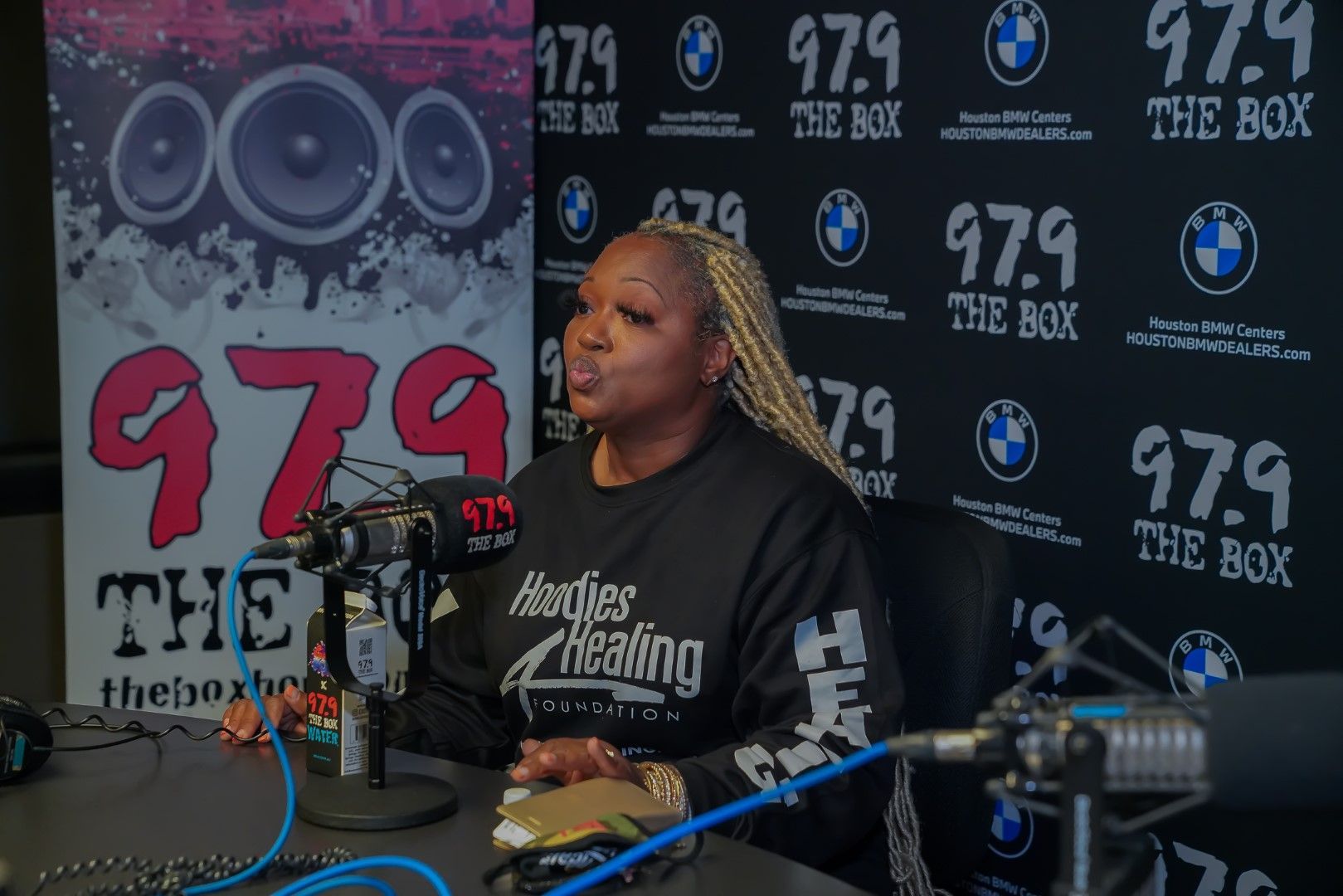A woman is sitting in front of a microphone in a radio studio.