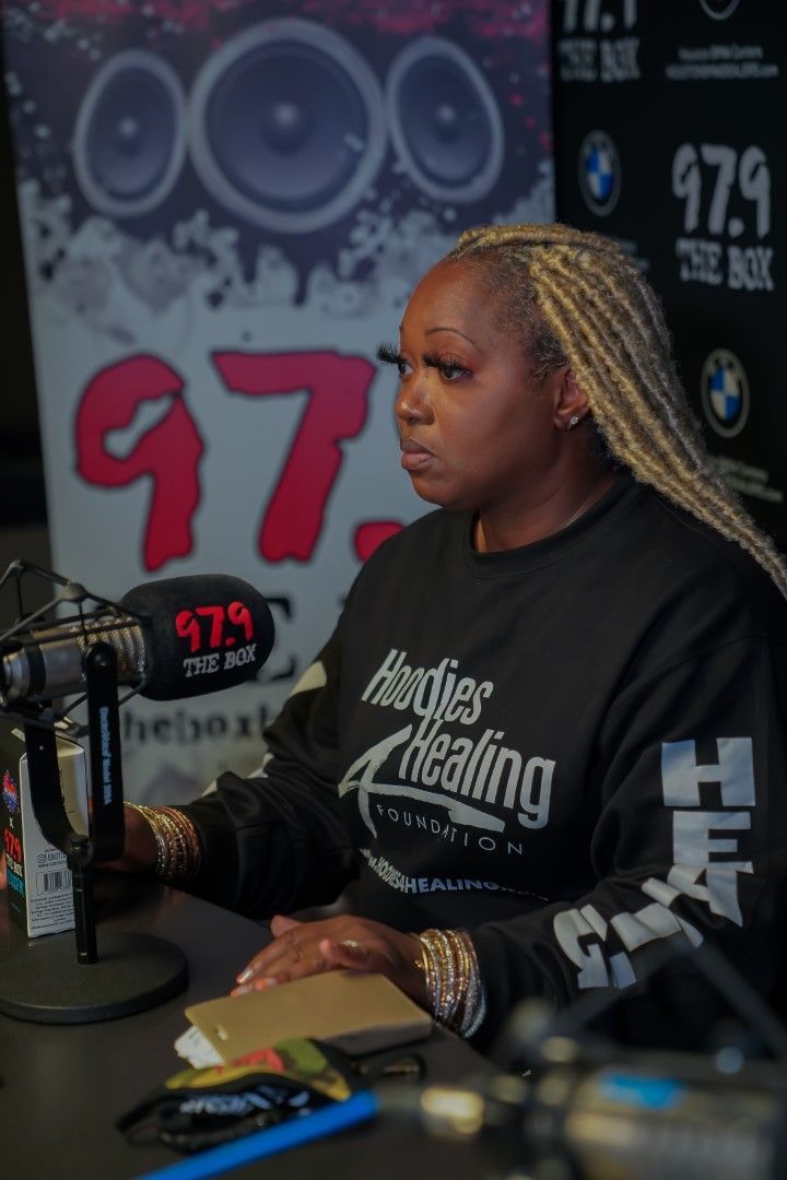 A woman sitting in front of a microphone wearing a shirt that says healing