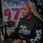 A woman is sitting in front of a microphone in a radio station.