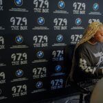 A woman is standing in front of a wall with a lot of logos on it.