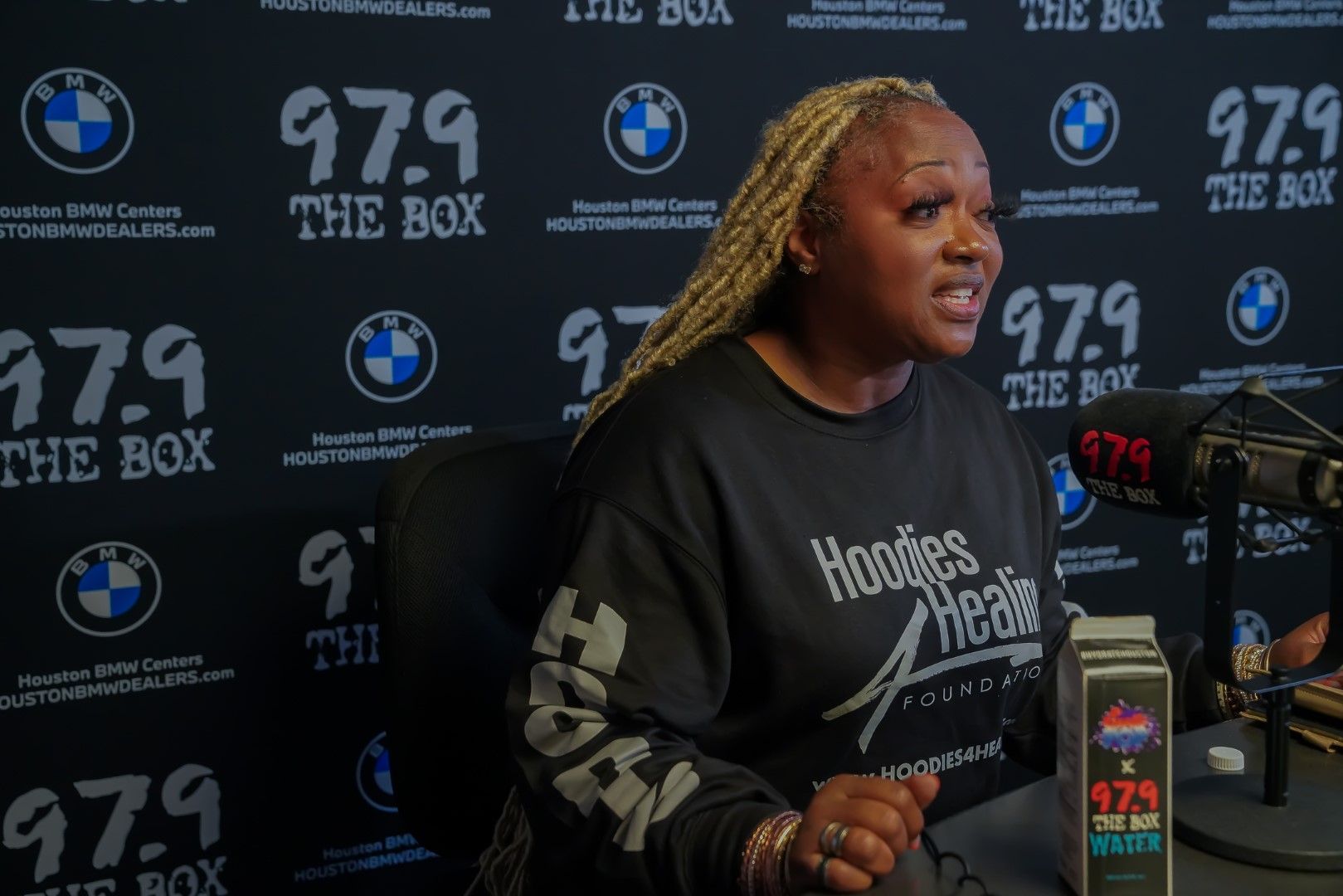 A woman is standing in front of a microphone in a radio studio.