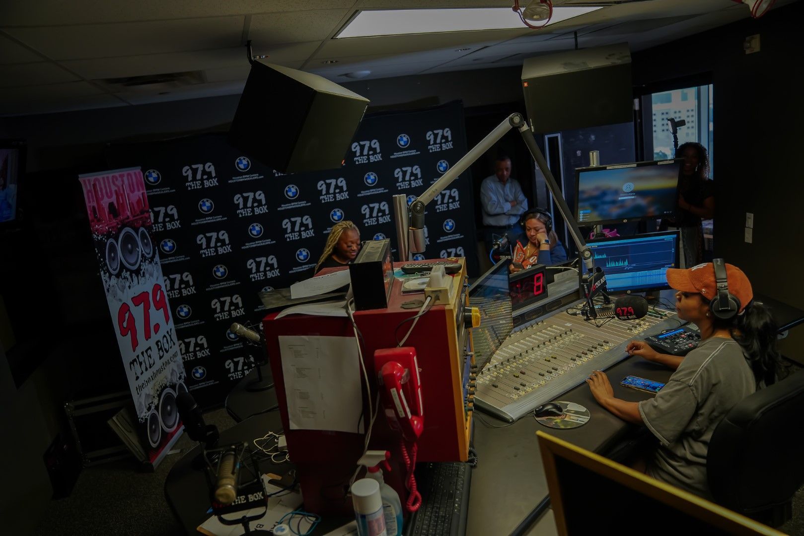 A group of people are sitting at a desk in a radio station.