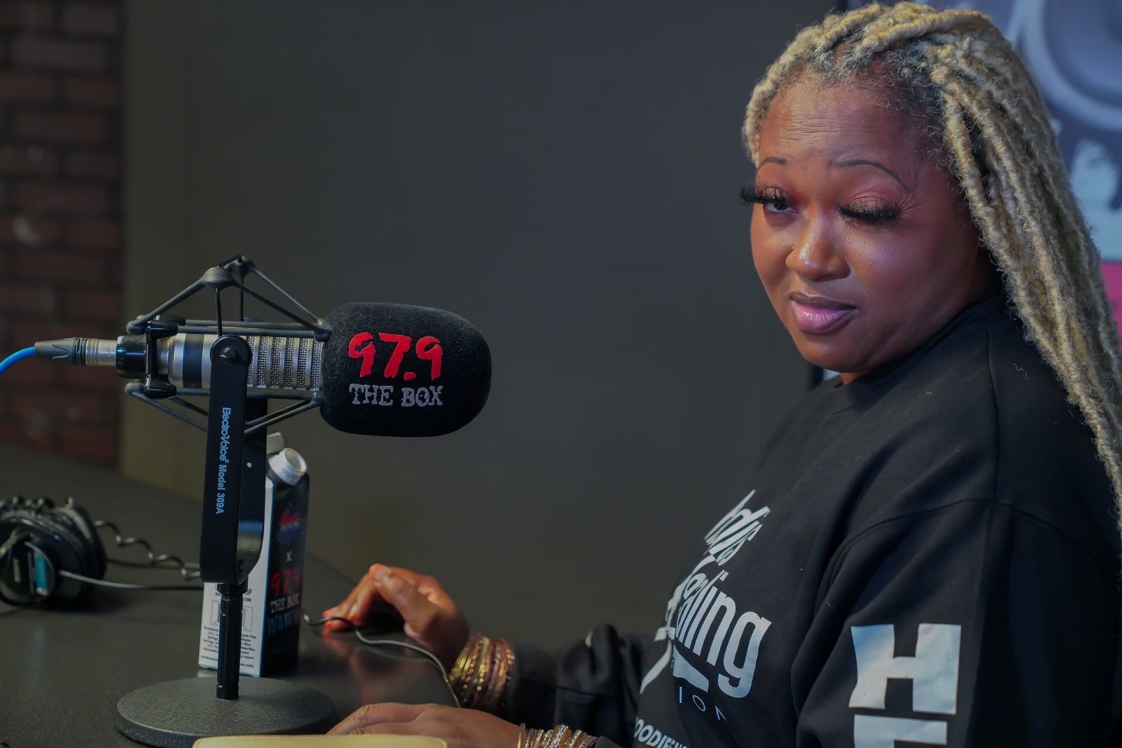 A woman is sitting in front of a microphone in a studio.