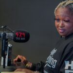 A woman is sitting at a desk in front of a microphone.
