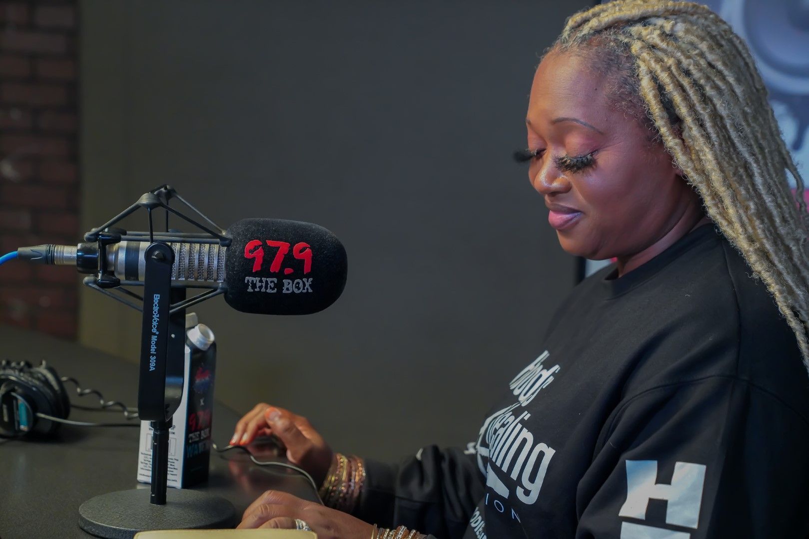 A woman is sitting in front of a microphone in a studio.