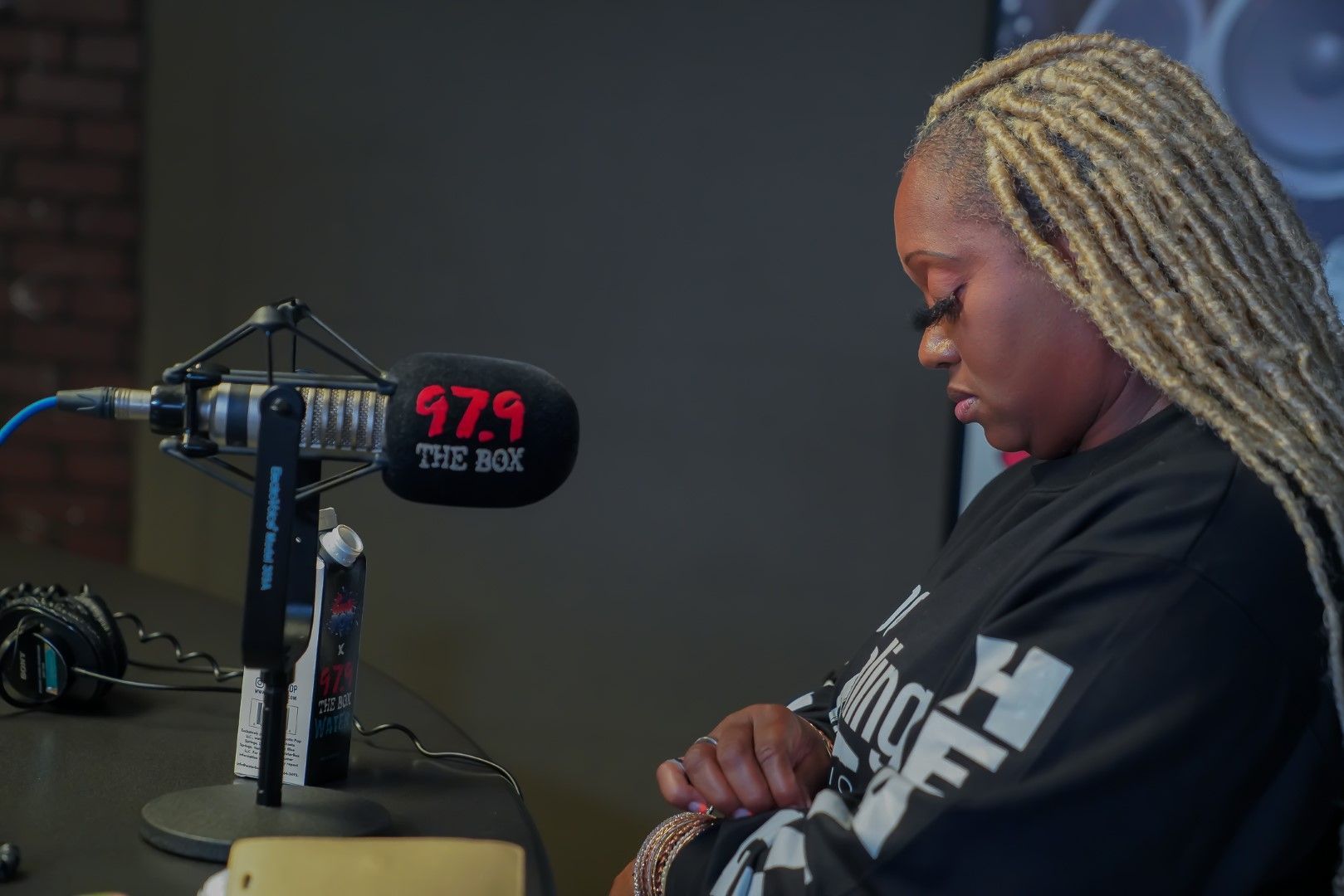 A woman with blonde braids is sitting in front of a microphone.