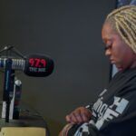 A woman is sitting in front of a microphone in a radio station.