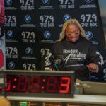 A woman is standing in front of a clock in a radio station.