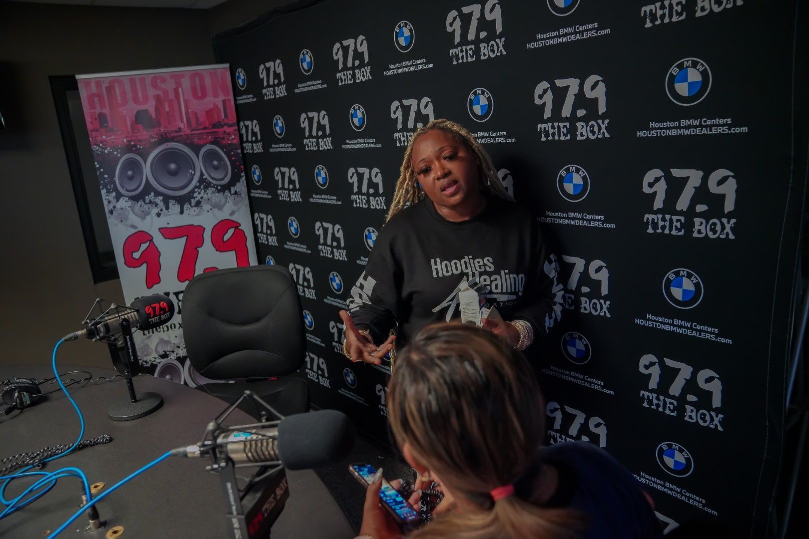 Two women are sitting in front of a microphone in a studio.