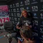 A woman is standing in front of a microphone in a room talking to a group of people.