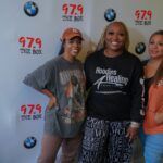 A group of women are posing for a picture in front of a wall.