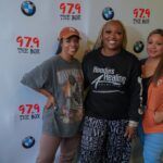 A group of women are posing for a picture in front of a wall.