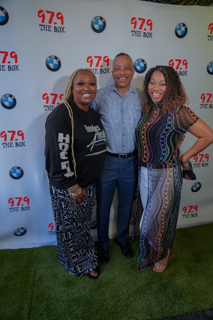 A man and two women are posing for a picture in front of a bmw backdrop.