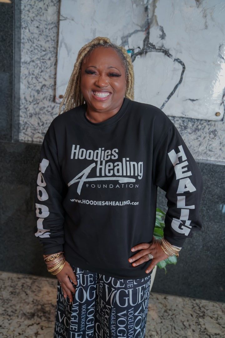 A woman wearing a black shirt that says hoodies healing