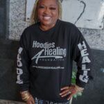 A woman is wearing a black hoodie and smiling.