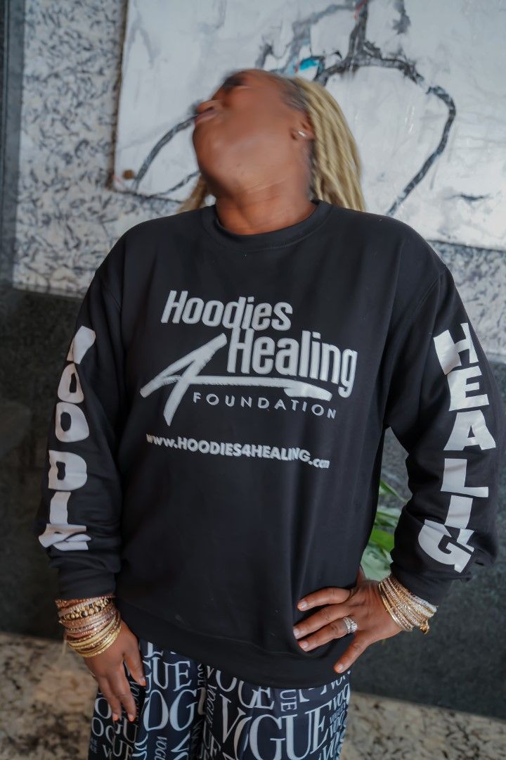 A woman wearing a black shirt that says hoodies healing foundation