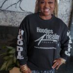 A woman is wearing a black hoodie and smiling.