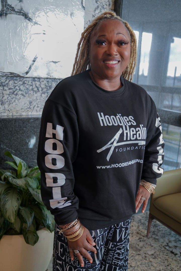 A woman wearing a black sweatshirt is standing in a room.