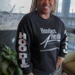 A man wearing a black sweatshirt is standing in a living room.