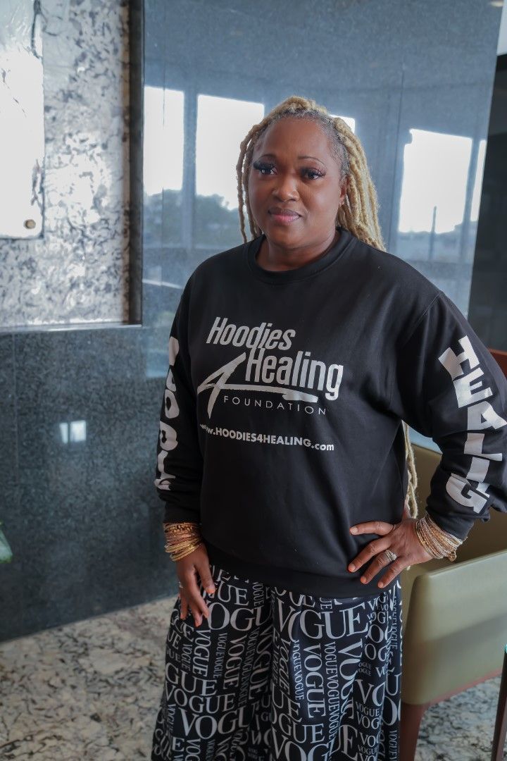 A woman wearing a black sweatshirt that says hoodies healing