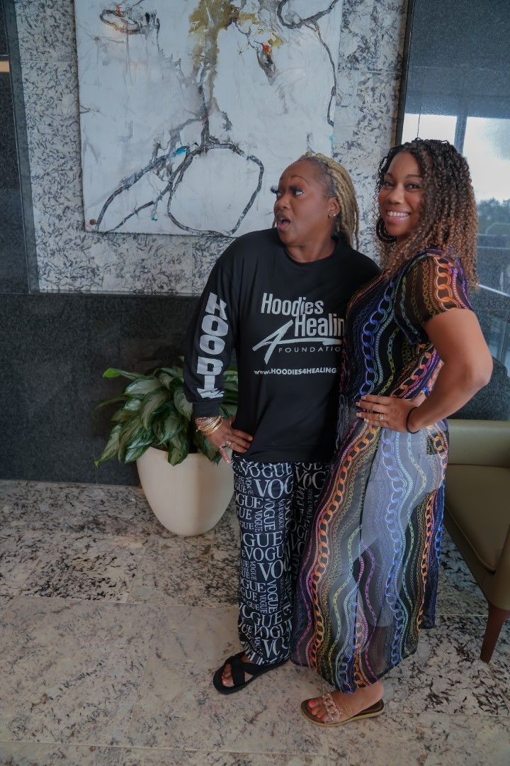 Two women are standing next to each other in front of a painting.