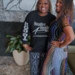 Two women are posing for a picture together in a living room.