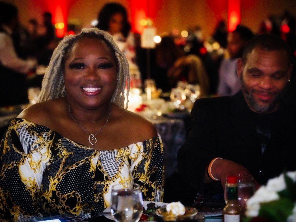 A woman is smiling while sitting at a table with a man.