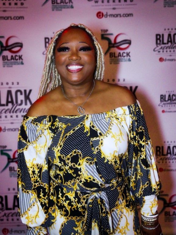 A woman stands in front of a wall that says black