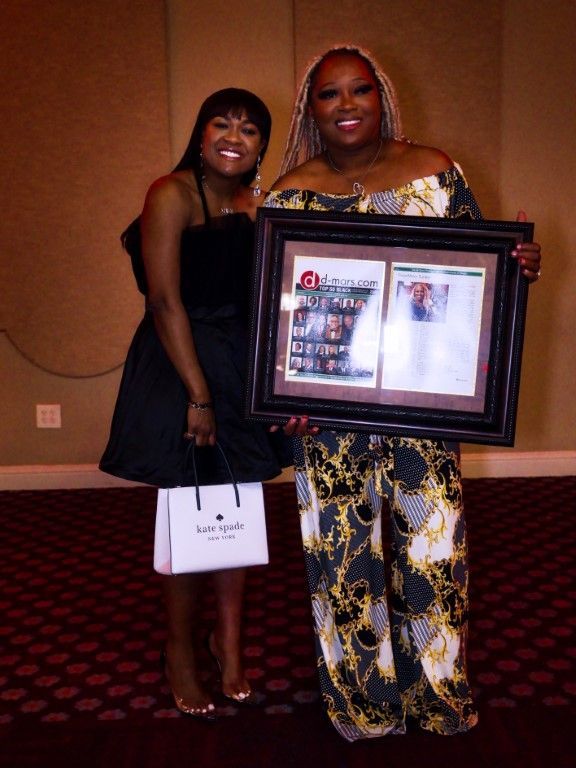 Two women standing next to each other holding a framed picture