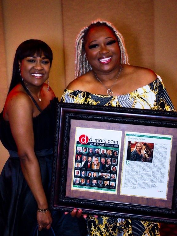 Two women holding a framed picture with a newspaper article on it