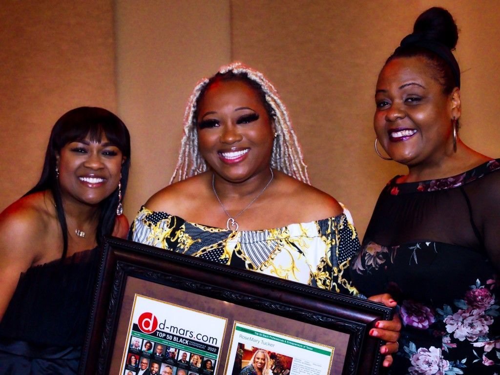 Three women are posing for a picture and one of them is holding a framed picture
