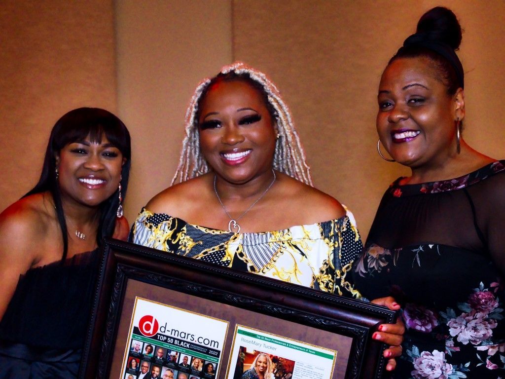 Three women are posing for a picture and one of them is holding a framed picture