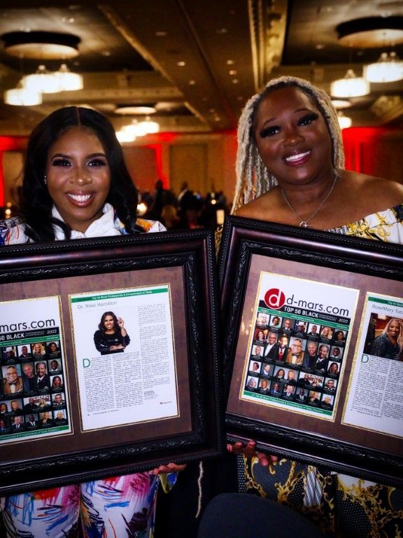 Two women are holding framed pictures of themselves in a room.
