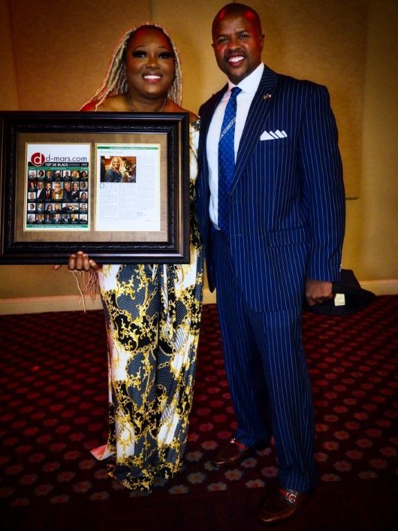 A man and a woman standing next to each other holding a framed picture