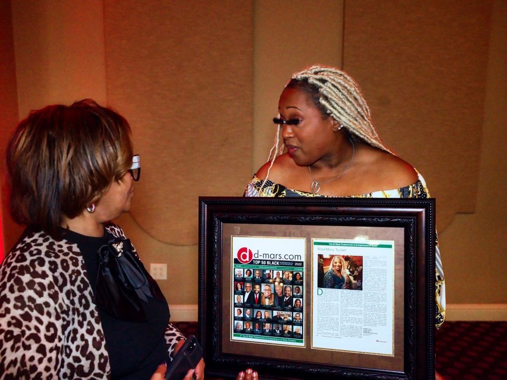 Two women are looking at a framed picture of a woman