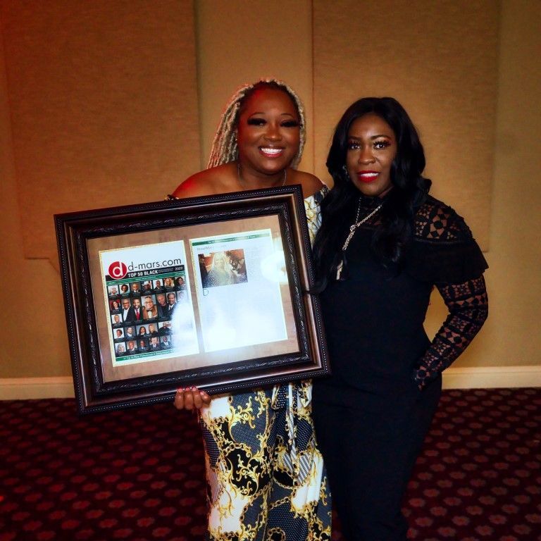 Two women standing next to each other holding a framed picture