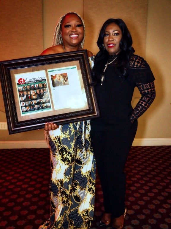 Two women standing next to each other holding a framed picture