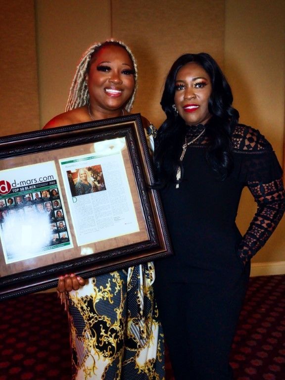 Two women standing next to each other holding a framed picture