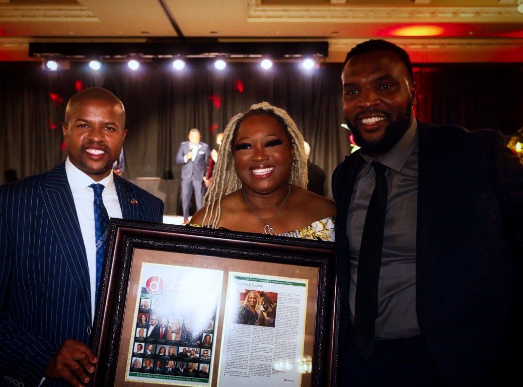 Two men and a woman are standing next to each other holding a framed picture.