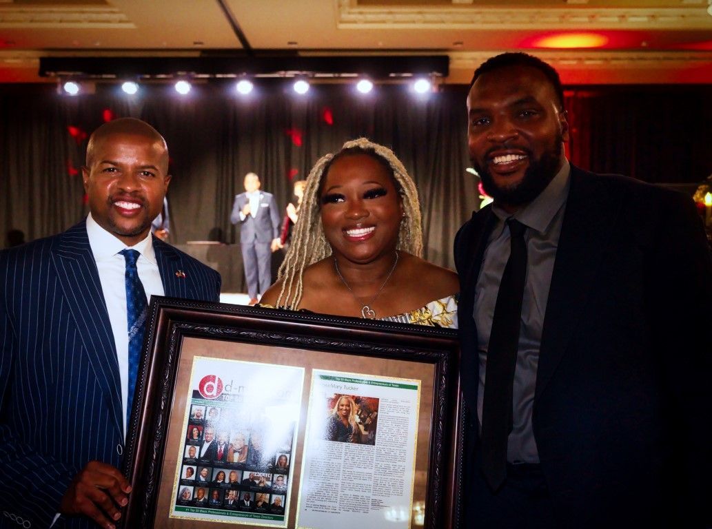 Two men and a woman are standing next to each other holding a framed picture.