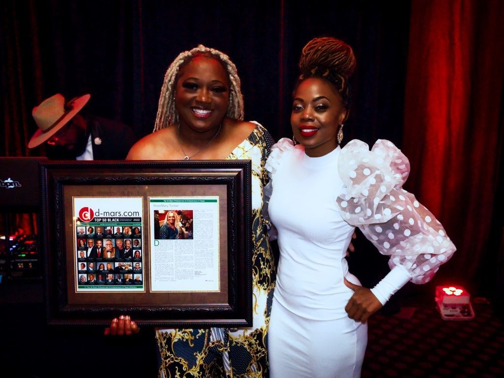 Two women are standing next to each other holding a framed picture.