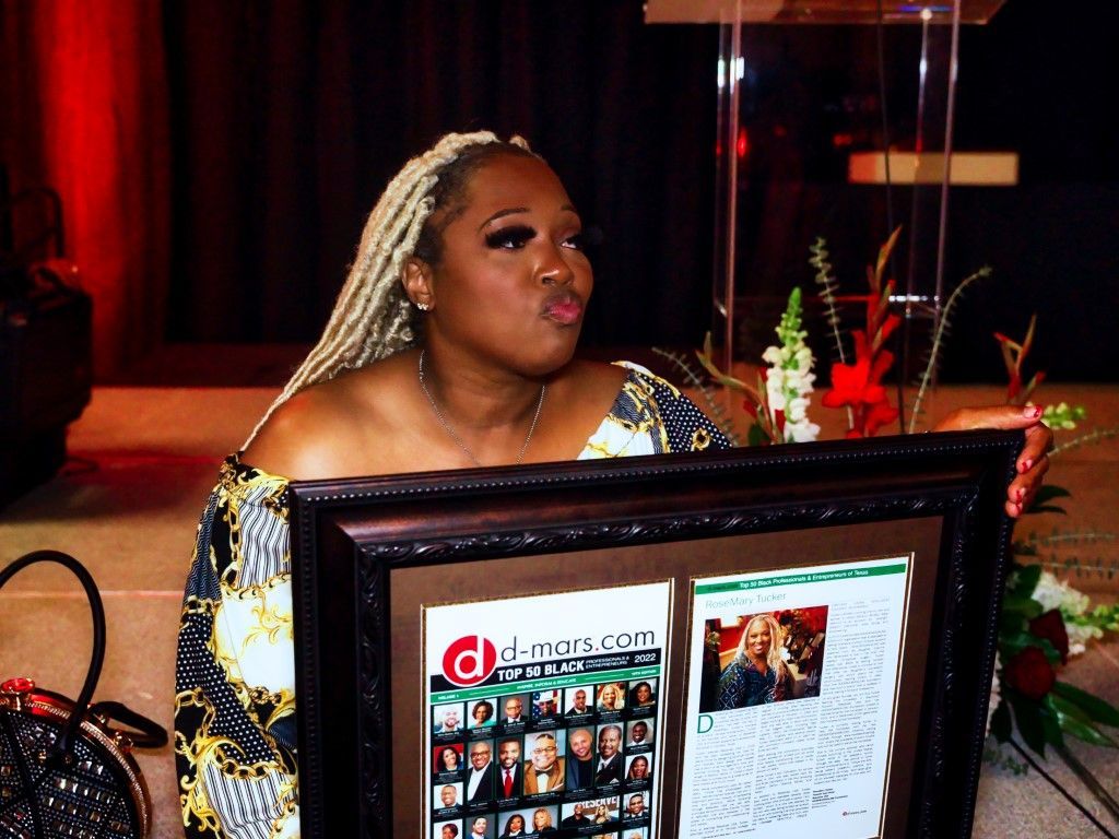 A woman is sitting at a podium holding a framed picture