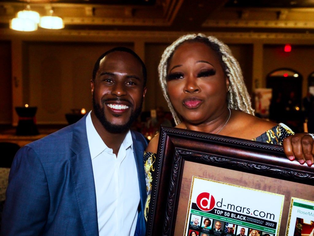 A man and a woman are posing for a picture while holding a framed picture.