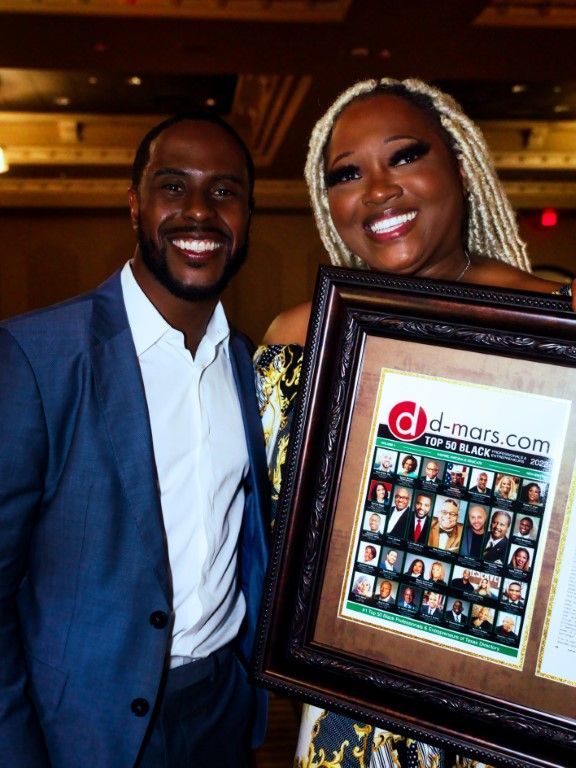 A man and a woman are holding a framed picture.