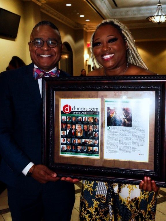A man and a woman are holding a framed picture that says g-d-news.com