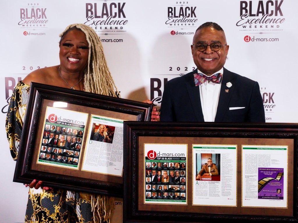 A man and a woman are standing next to each other holding framed pictures.
