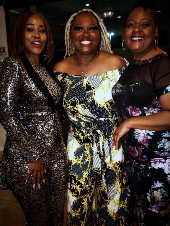 Three women are posing for a picture and smiling for the camera