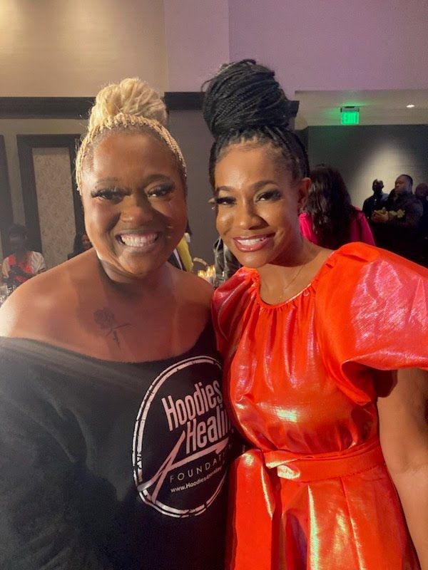 Two women are posing for a picture together and one is wearing a red dress.